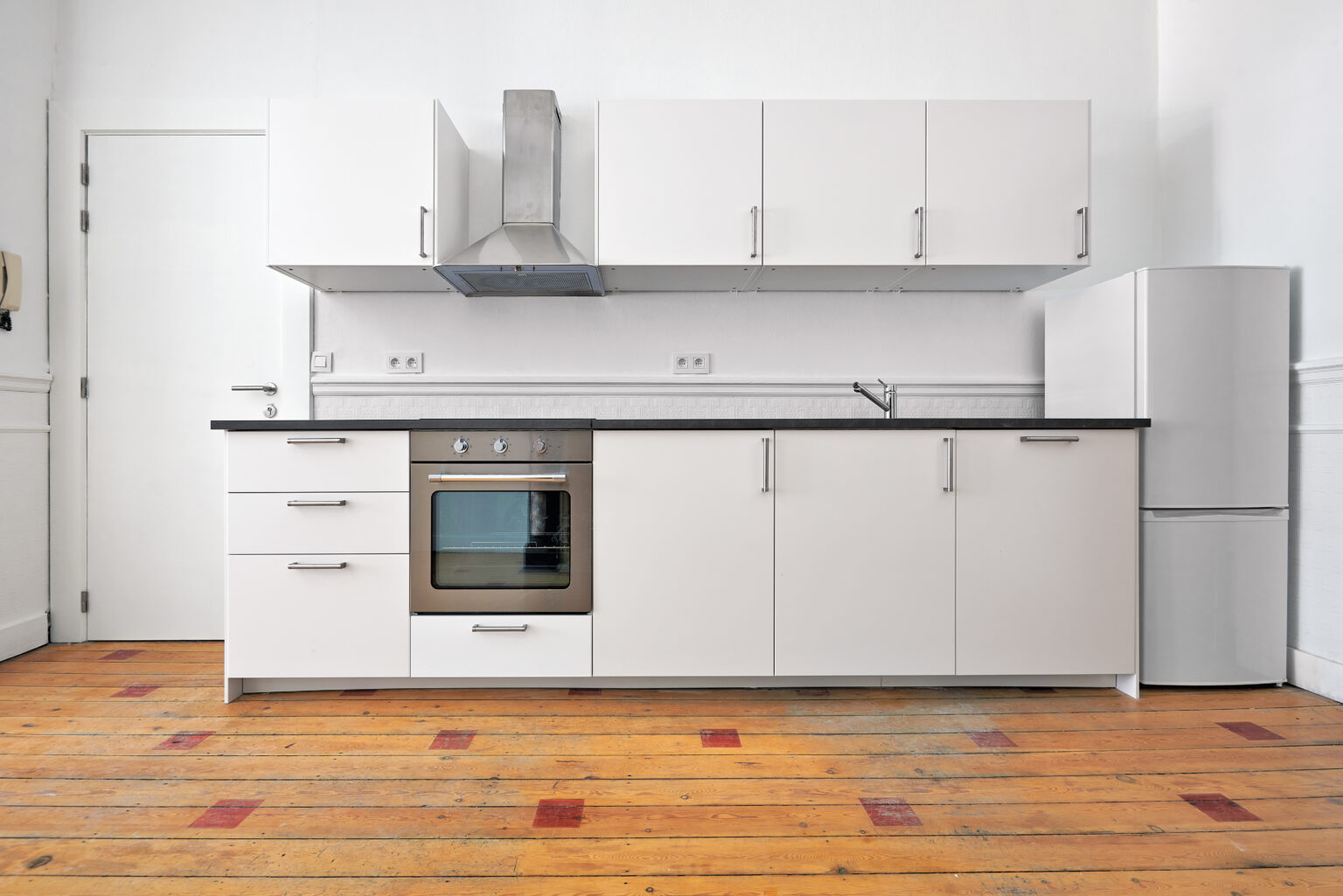 Empty apartment with modern kitchen and designed hardwood floor after renovation