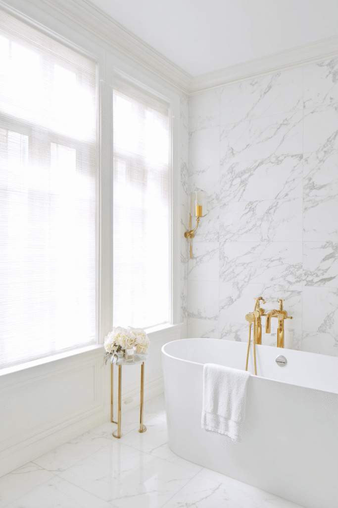 Luxury bathroom renovation in Toronto featuring marble walls, freestanding bathtub, and brass fixtures showing a high-end bathroom renovation design.