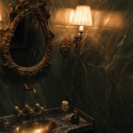 Moody luxury bathroom renovation in Toronto with dark green marble walls, brass fixtures, and vintage mirror in a French-inspired design.