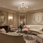 French classic basement lounge with beige tones, ornate wall moldings, chandelier, and curved sofa for a luxury basement renovation