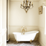 Elegant small bathroom renovation ideas with a clawfoot bathtub, marble walls, brass fixtures, and natural light for a timeless luxury look.