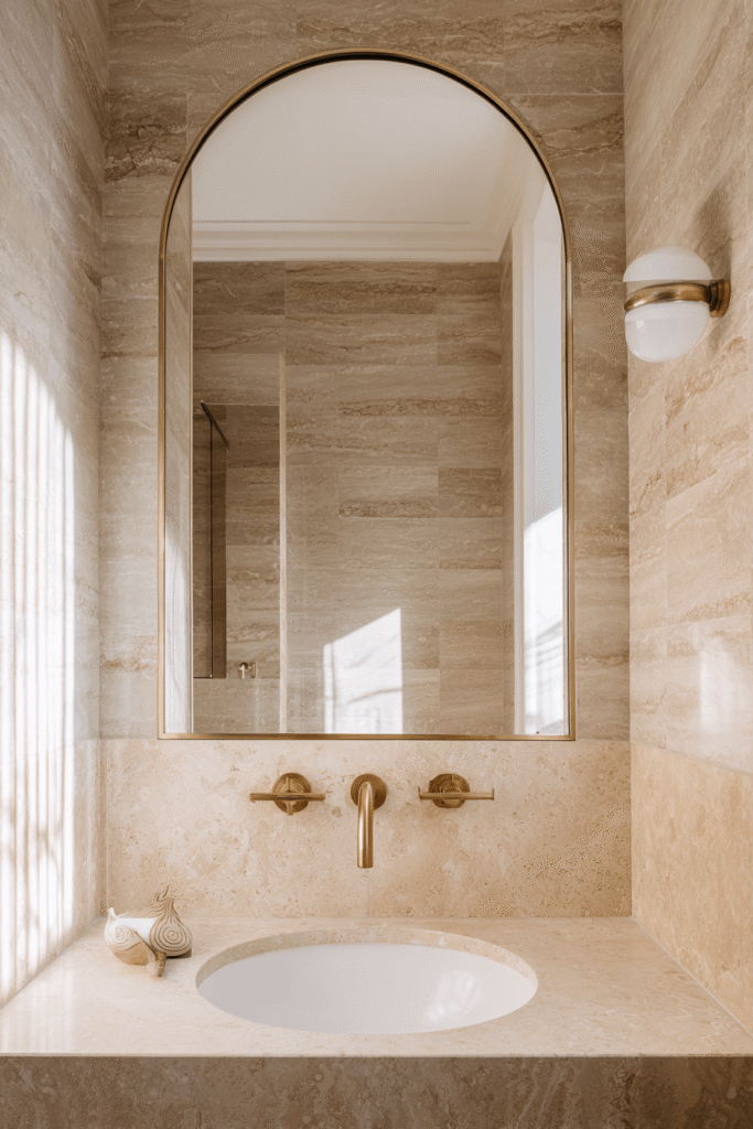 Small bathroom renovation Toronto with warm neutral tones, modern stone sink, and arched mirror design