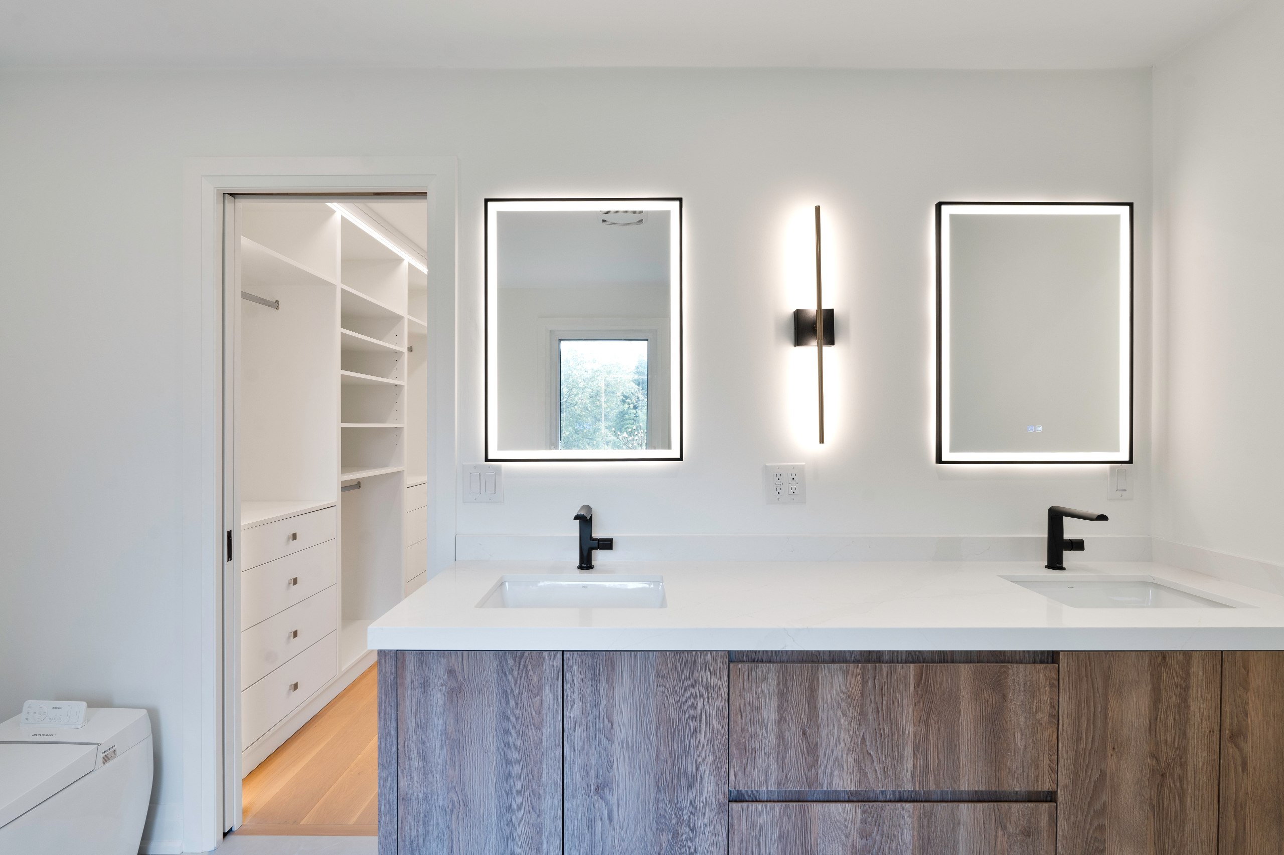 Ensuite bathroom renovation in Toronto with double vanity, illuminated mirrors, and custom wood cabinetry