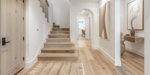 Artsy finished basement hallway with light wood stairs, white walls, natural textures, and warm decor, showing a polished approach to renovating basement entry spaces.